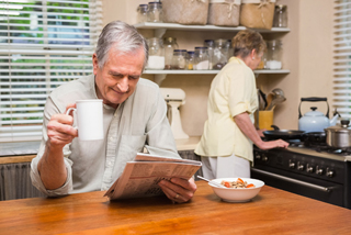 Older man enjoying breakfast with his wife in their kitchen