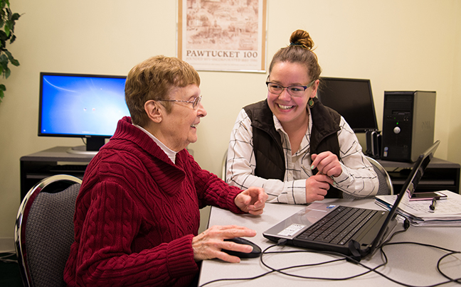 Cyber-Seniors volunteer Sally Dean, at right, shares a laugh with
Brenda Beauregard while learning to post images to Facebook on her laptop.