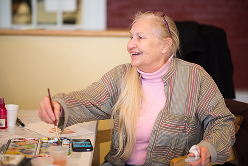 Judy Hamin, dips her brush in paint.