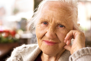 Elderly woman smiles while looking into camera lens